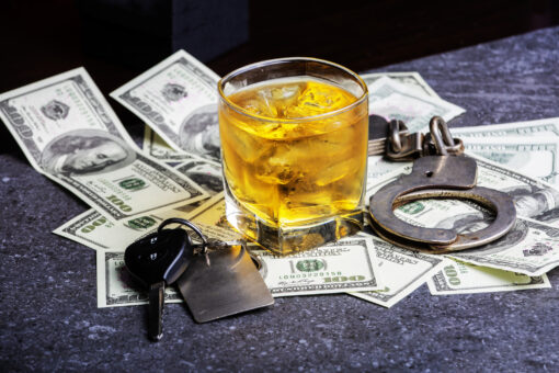 Car keys, alcohol, dollars and handcuffs to illustrate that you will go to jail if you dink and drive