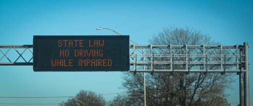 An overhead highway sign reminds drivers that driving while impaired is illegal.