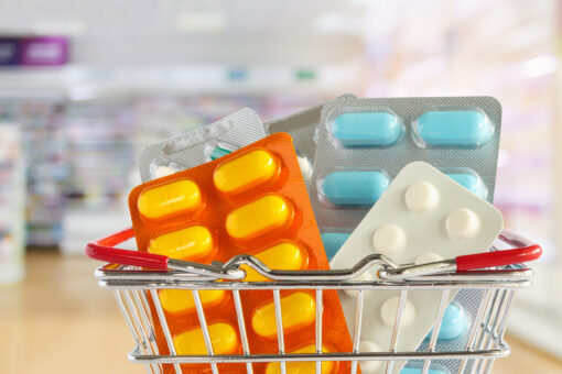 Medicine pill tablet in shopping basket with pharmacy drugstore shelves blurred background